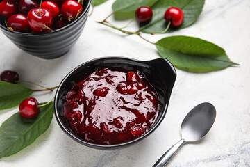 Bowl with sweet cherry jam on light background