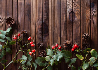 Fototapeta na wymiar Сhristmas decoration on wooden background. Cones, needles, rose hips. Warm and cozy postcard.