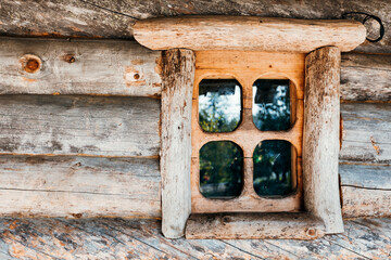 An old traditional rustic wooden house (log cabin) with small windows. A window in a wooden house.