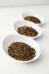 Bowls of dry hojicha green tea on light background