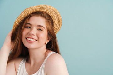 Young ginger woman in straw hat smiling and looking at camera