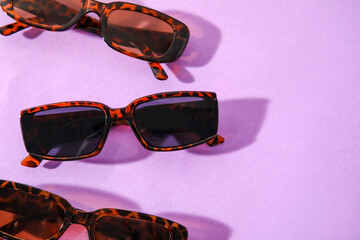 Stylish female sunglasses on color background, closeup