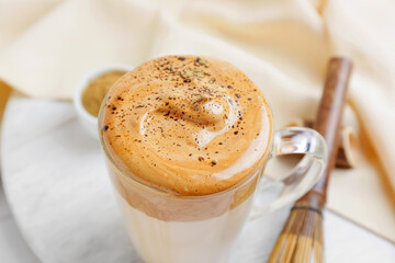 Glass cup of tasty dalgona hojicha latte on table, closeup
