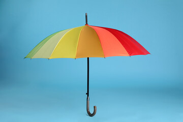 Stylish open bright umbrella on light blue background