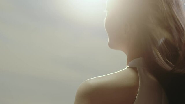 close-up rear view of Asian beauty standing and facing the sun with long hair flying in wind