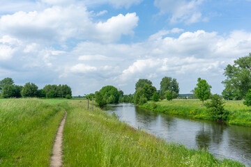 Fahrradweg entlang des Flusses "Rur" umgeben von grünen Feldern und Bäumen