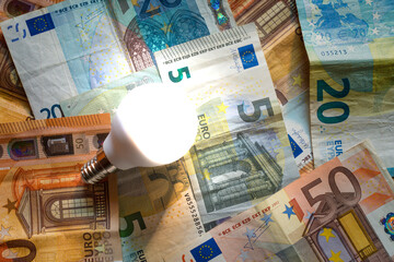 Light bulb on a background of euro banknotes.