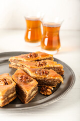 Tray with tasty baklava on light wooden background, closeup