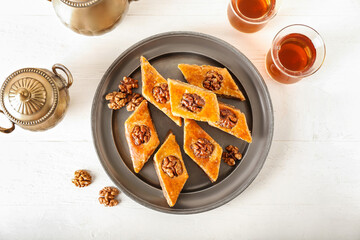 Tray with tasty baklava and glasses of Turkish tea on light wooden background