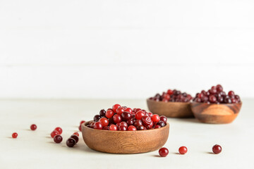 Bowls with healthy cranberries on light background