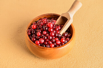Bowl and scoop with healthy cranberries on color background