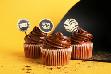 Tasty cupcakes for New Year 2022 celebration on color background