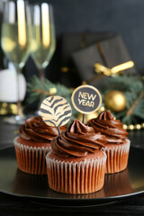 Plate with tasty cupcakes for New Year 2022 celebration on table