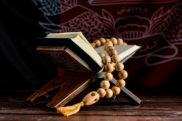 Fototapeta na wymiar Koran and tasbih on table against dark background