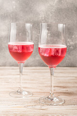 Two glasses of rose cocktails. Sparkling red cocktail with ice made at home. Vertical image