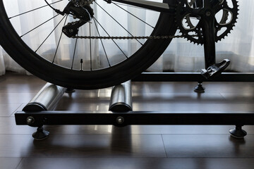 detail of road bike on rolling trainer in private space, indoor bike training at home during...
