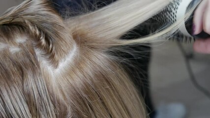 Female hands of a professional hairdresser dry hair with a hairdryer and do styling in a hairdressing salon.