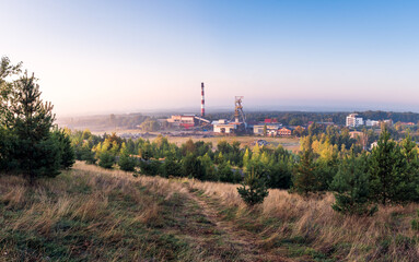 Fototapeta na wymiar Beautiful view on coal mining 'Boze Dary' in Katowice, Silesia, Poland seen from mining heap at sunrise. Nature versus industry. A mine surrounded by forests. Mining infrastructure.