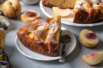 Sliced peach pie sprinkled with powdered sugar on light gray table. Close-up