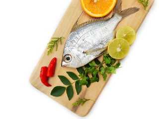 Gerres Fish (Gerres Filamentosus) , Whipfin silver biddy Fish , Decorated with curry Leaves and Tomato on a Wooden pad,White Background.Selective focus.