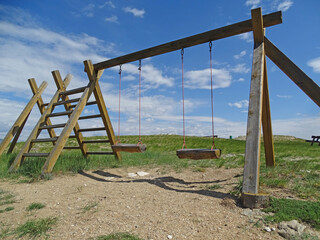 children's swing made of wooden logs in a rustic style