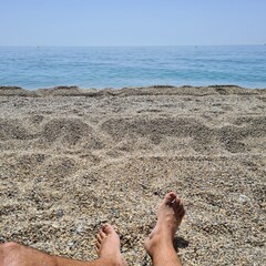 The legs of a man on the sand of the beach sunbathing. Enjoying your vacation on a beautiful beach