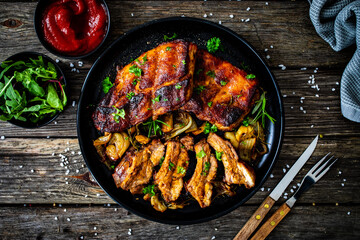 Tasty roasted ribs with onion and garlic on wooden table
