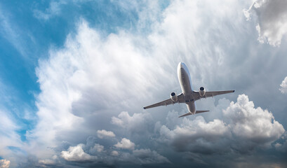 Fototapeta na wymiar White passenger airplane over the stormy dark clouds - Travel by air transport