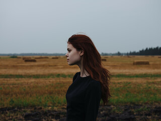 cute red-haired woman in black dress in field travel fashion