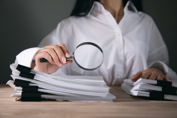 woman holding magnifying glass and documents