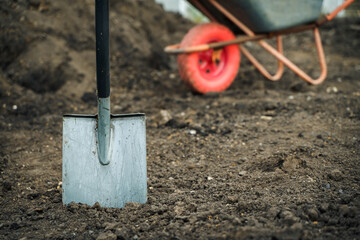 Working with garden tools, shovel and wheelbarrow on the site of a country house. Preparation for...