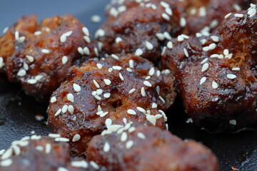 Sticky Asian cauliflower bites battered, deep-fried and tossed in Asian BBQ sauce, sprinkled with toasted sesame seeds and spring onion