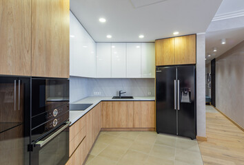 Modern interior of light wooden kitchen in apartment. White cabinets.