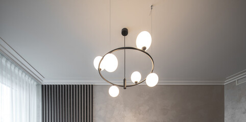 Modern designed chandelier with burning lamps. Contemporary interior.