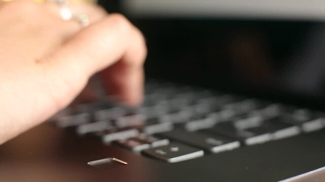 Close up of woman touching laptop fingerprint sensor with her finger to login. Biometric fingerprint print scan provides security access with user identification. Computer privacy and security.