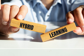 Hybrid learning symbol. Concept words 'Hybrid learning' on wooden blocks. Businessman hand....