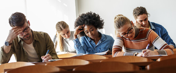 University students taking a test in a classroom.Educational concept.  © BalanceFormCreative