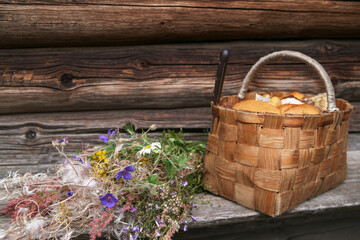 Composition with a basket full of mushrooms and wildflowers on a natural wooden background.