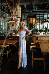 Portrait of a beautiful young attractive blonde girl in a summer dress in an atmospheric cafe