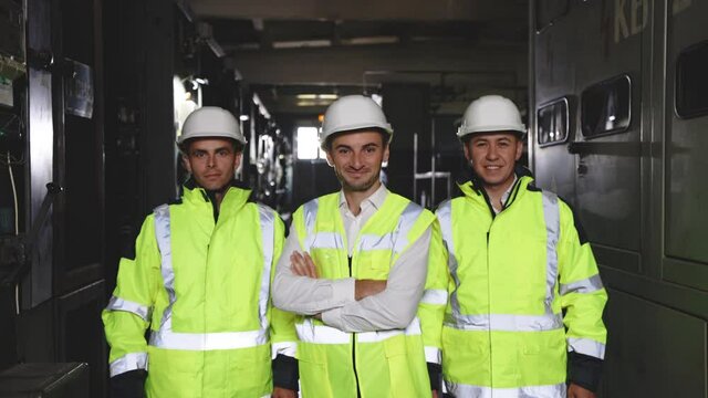 Portrait of group of professional telecommunication industry engineers smiles and looks at the camera . Workers wearing safety uniform and hard hat on unfocused background