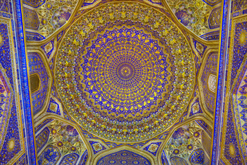 Details of the vaulted ceiling in golden-blue tones, an example of Central Asian architecture. Tilya Kori Madrasah in Samarkand, Uzbekistan, 17th century