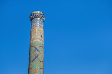 Minaret of Bibi Khanym mosque against background of blue sky. Tower is decorated with traditional oriental patterns. Shot in Samarkand, Uzbekistan