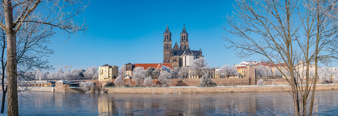 Panoramic view over Magdeburg historical downtown in Winter with icy trees and snow during sunrise...