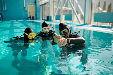 Instructor and divers in aqualungs, dive lesson