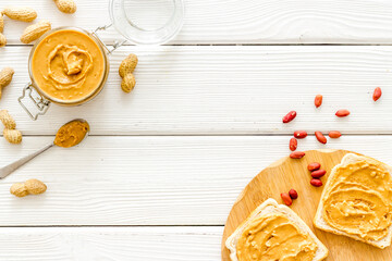 Bowl of peanut butter with nuts on kitchen table. Overhead view