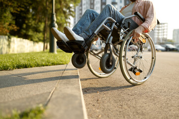 Disabled man in wheelchair overcomes the curb