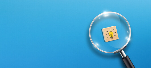 Creative idea concept, magnifying glass and light bulb icon on wooden block with blue background