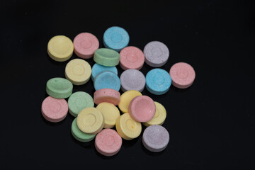 a bunch of 6 colored pills on black