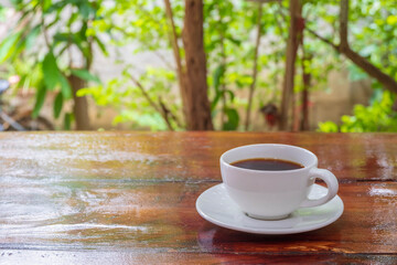 A cup of coffee on a wooden table in the morning with the late morning sunlight.A cup of coffee on a wooden table in the morning with the late morning sunlight.