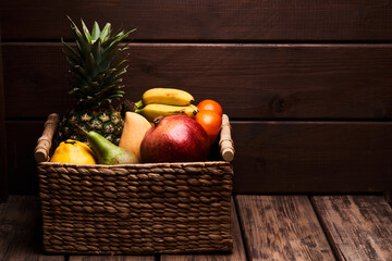 Mix of fresh juicy colorful exotic tropical fruits in basket on wooden background